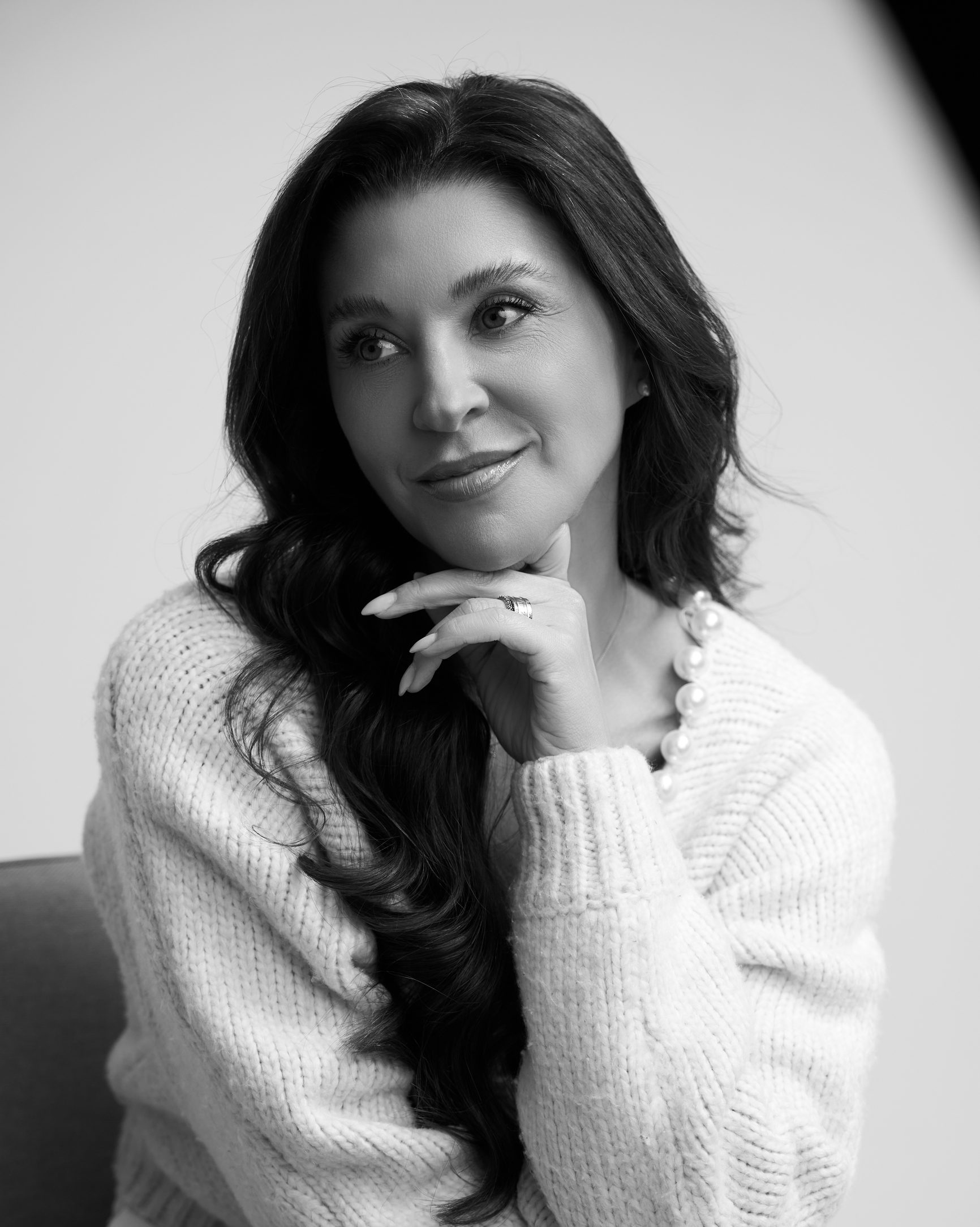 Retrato em preto e branco da Dra. Carolina Rosa sorrindo, com a mão no rosto