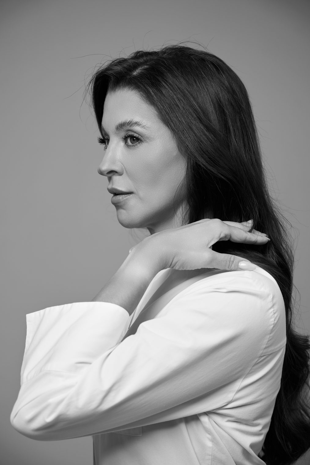 Retrato em preto e branco da Dra. Carolina Rosa de perfil, com jaleco branco e a mão apoiada no ombro